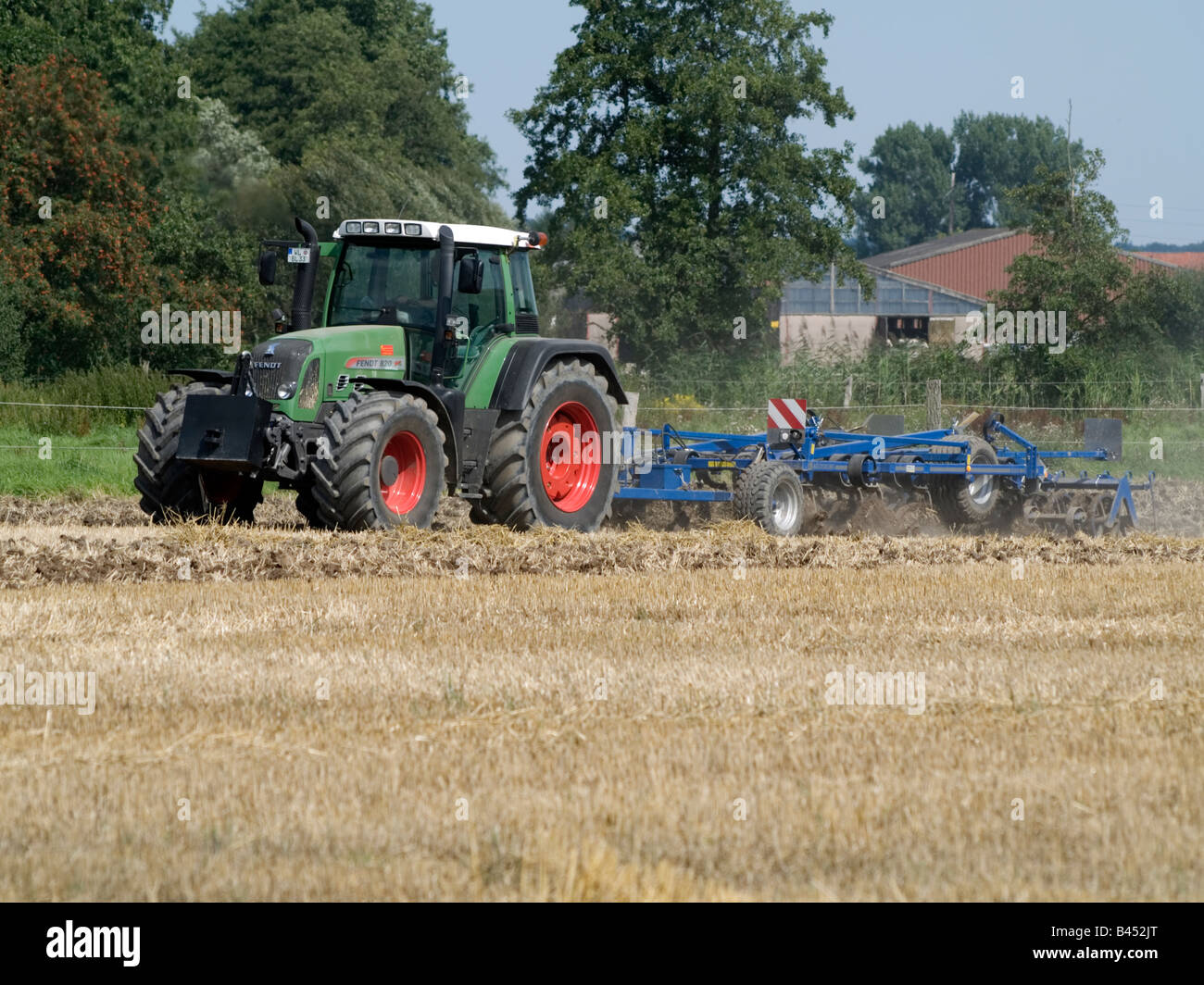Farmer with his tractor harrowing the field after grain harvest Stock ...