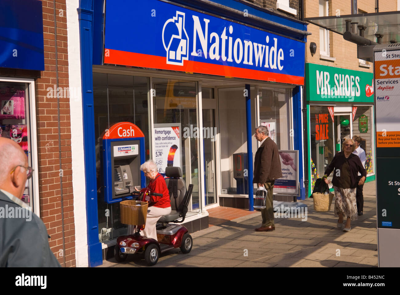 Woman on motability scooter using speedbank machine at Nationwide Building Society in Norwich,Norfolk,Uk Stock Photo