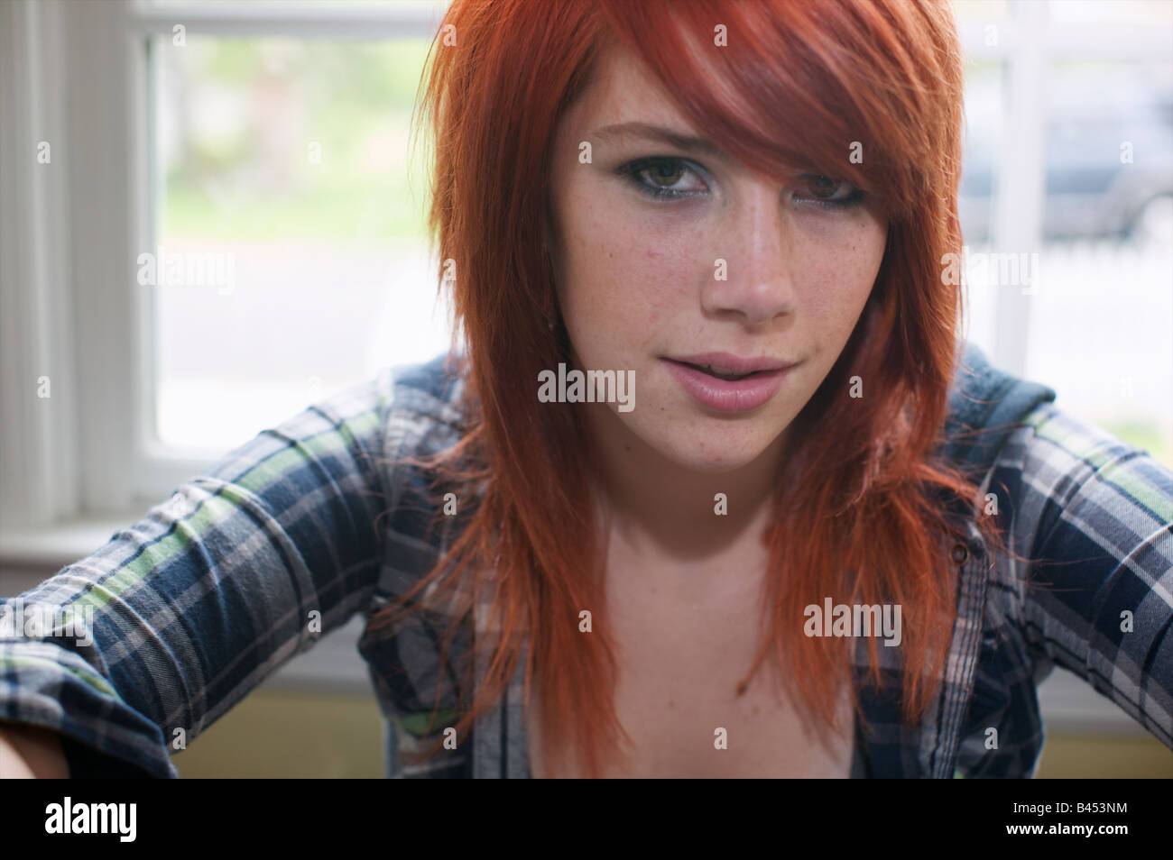 Cute teenager with freshly dyed orange hair take a self portrait of herself in flannel and tank top. Stock Photo