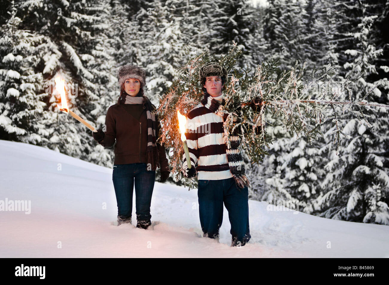 Austria, Salzburger Land, Altenmarkt, Young couple with fir tree and torches in the snow Stock Photo
