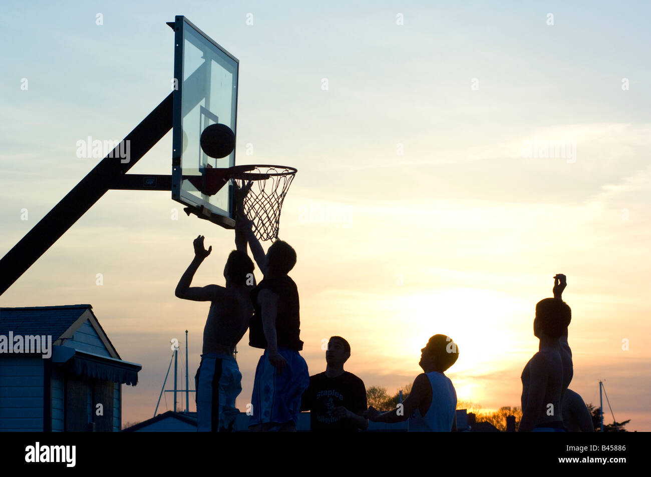 Basketball players shooting basket at sunset in outdoor park, Westport, Ct. Stock Photo