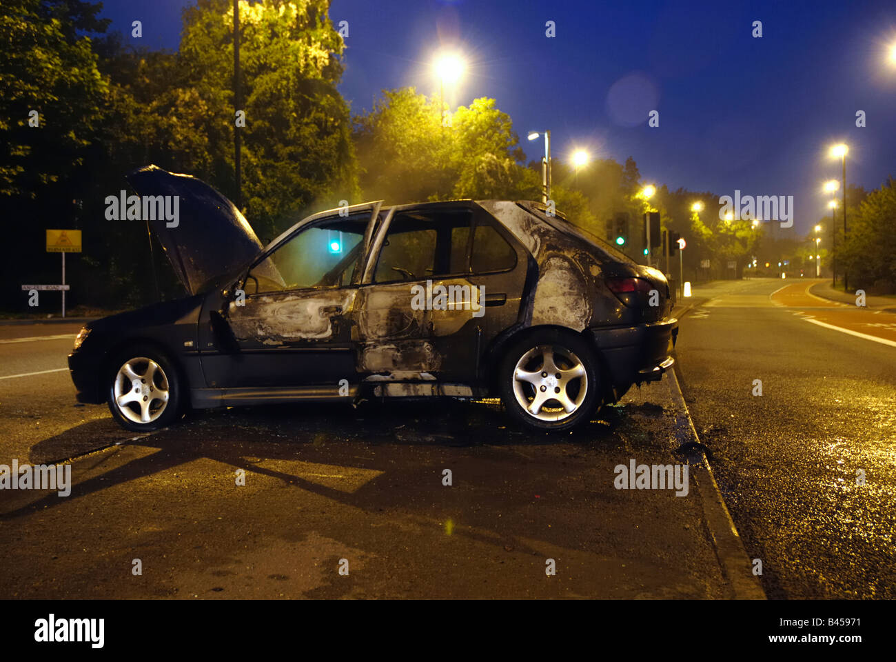 Burned out  car attended to by the police in the early hours of the morning Stock Photo