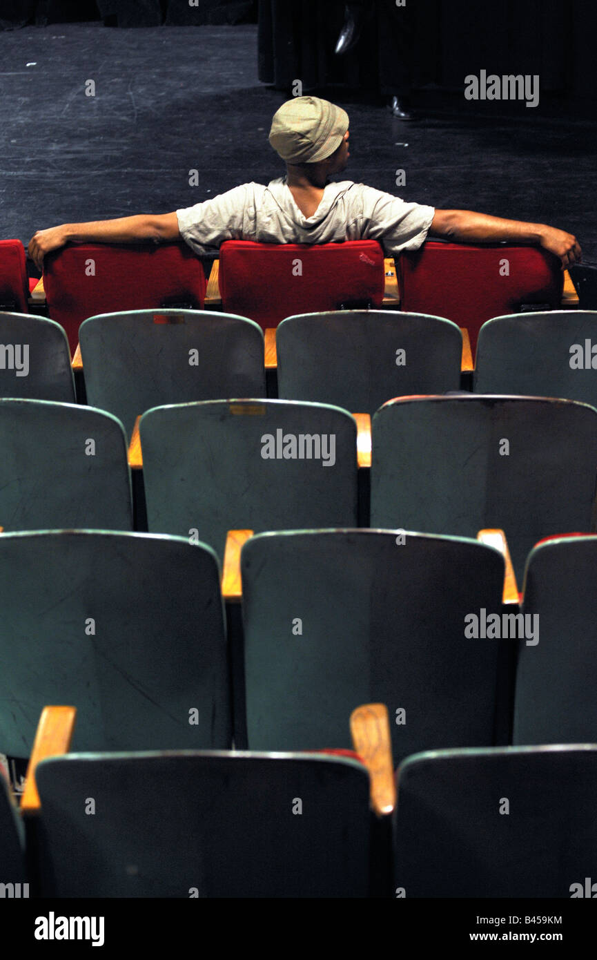 A spectator in a theatre sits in the front row in front of the stage. Stock Photo