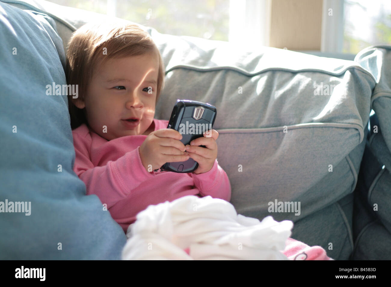 A 17-month-old toddler girl is excited by an email she is reading on a Blackberry device. Stock Photo