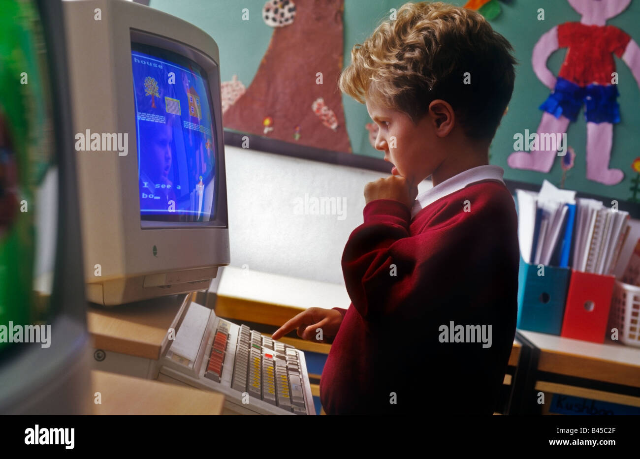 Infant school boy in class room aged 4 to 6 years looks at computer screen to identify and learn screen displayed object names Stock Photo
