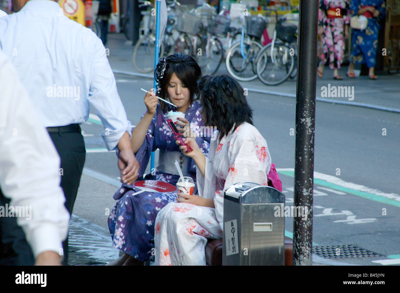 Two young Japanese girls wearing traditional kimonos outside in an urban setting Stock Photo