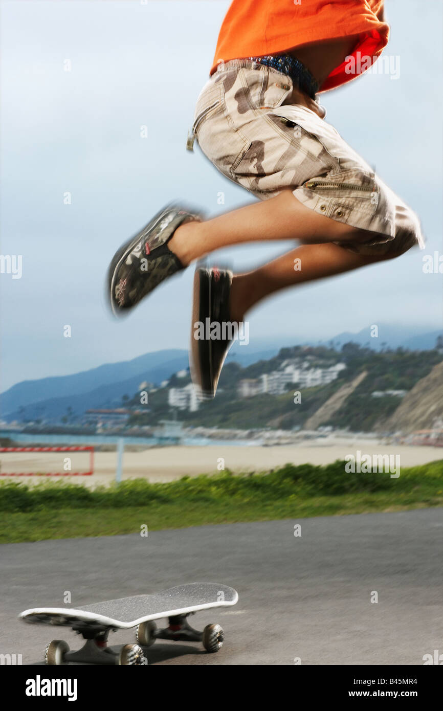 Mixed Race boy jumping over skateboard Stock Photo - Alamy