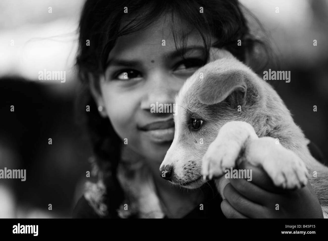 Young Indian village girl holding a puppy. Andhra Pradesh, India. Black and White Stock Photo