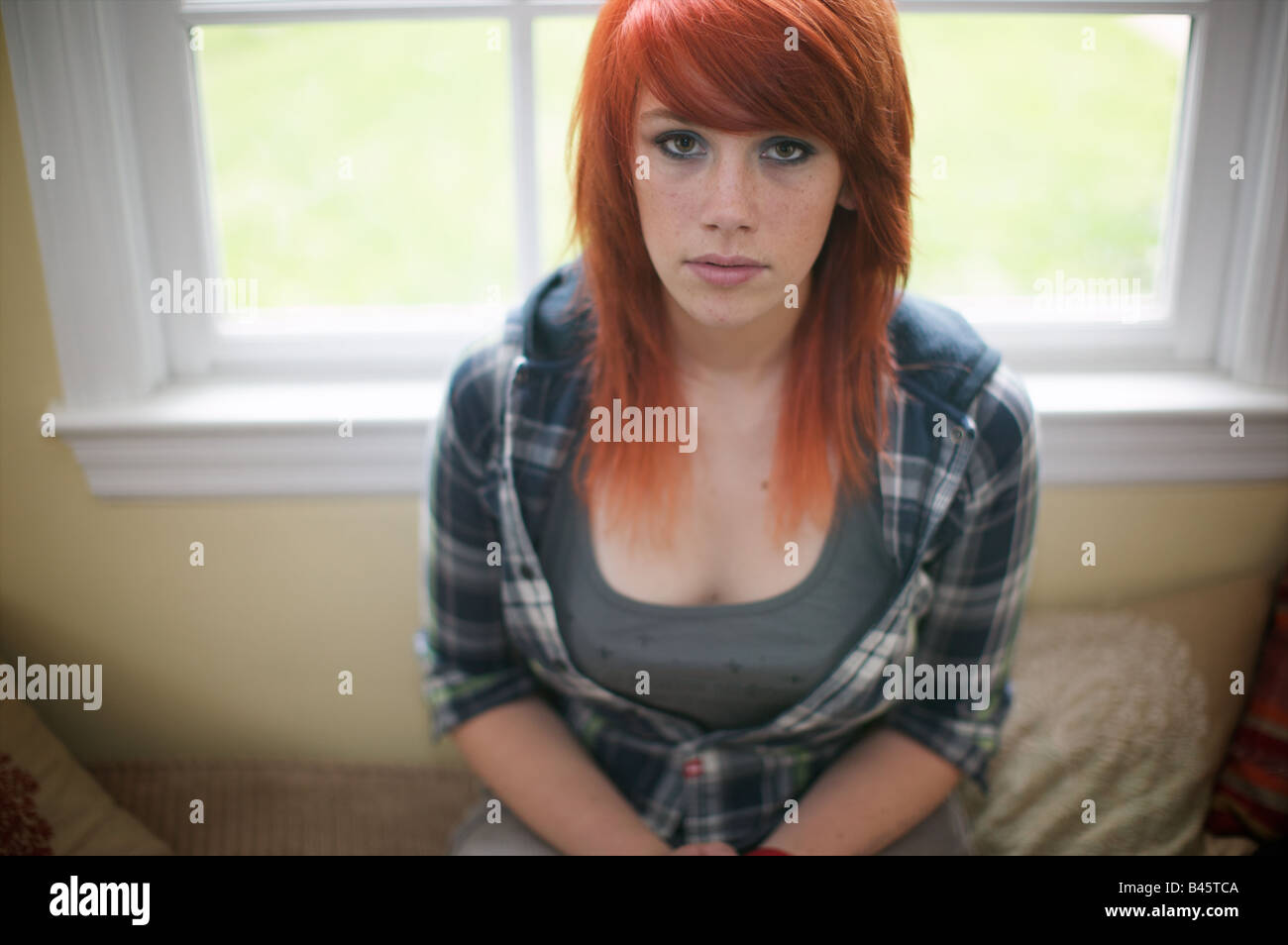 Girl with shocking orange hair and blue flannel work shirt gazes  disconsolately at camera. It's a sunny day, but raining inside Stock Photo  - Alamy
