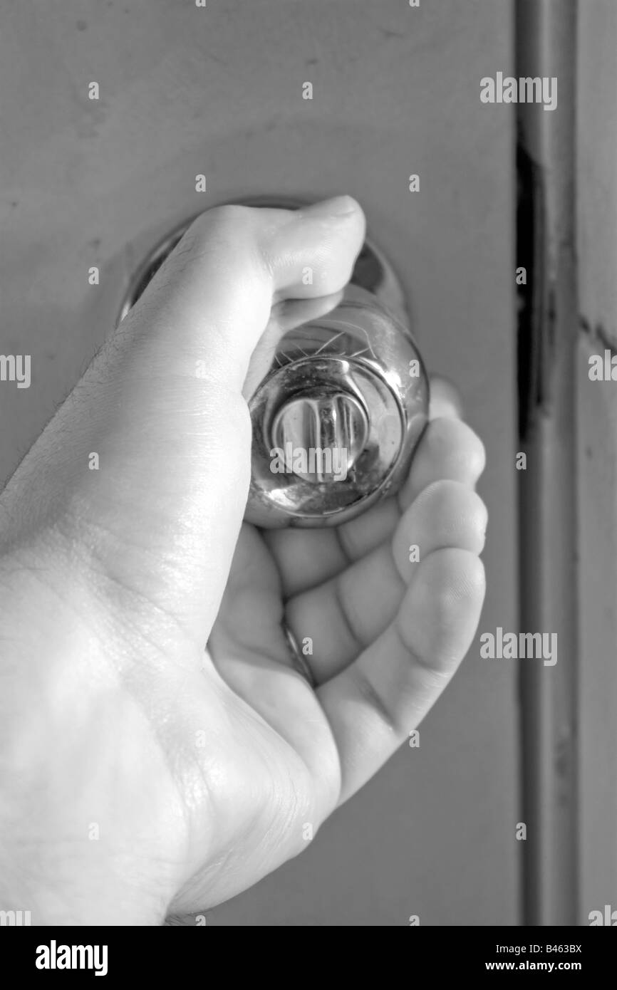 A hand grasping a shiny doorknob in black and white Stock Photo