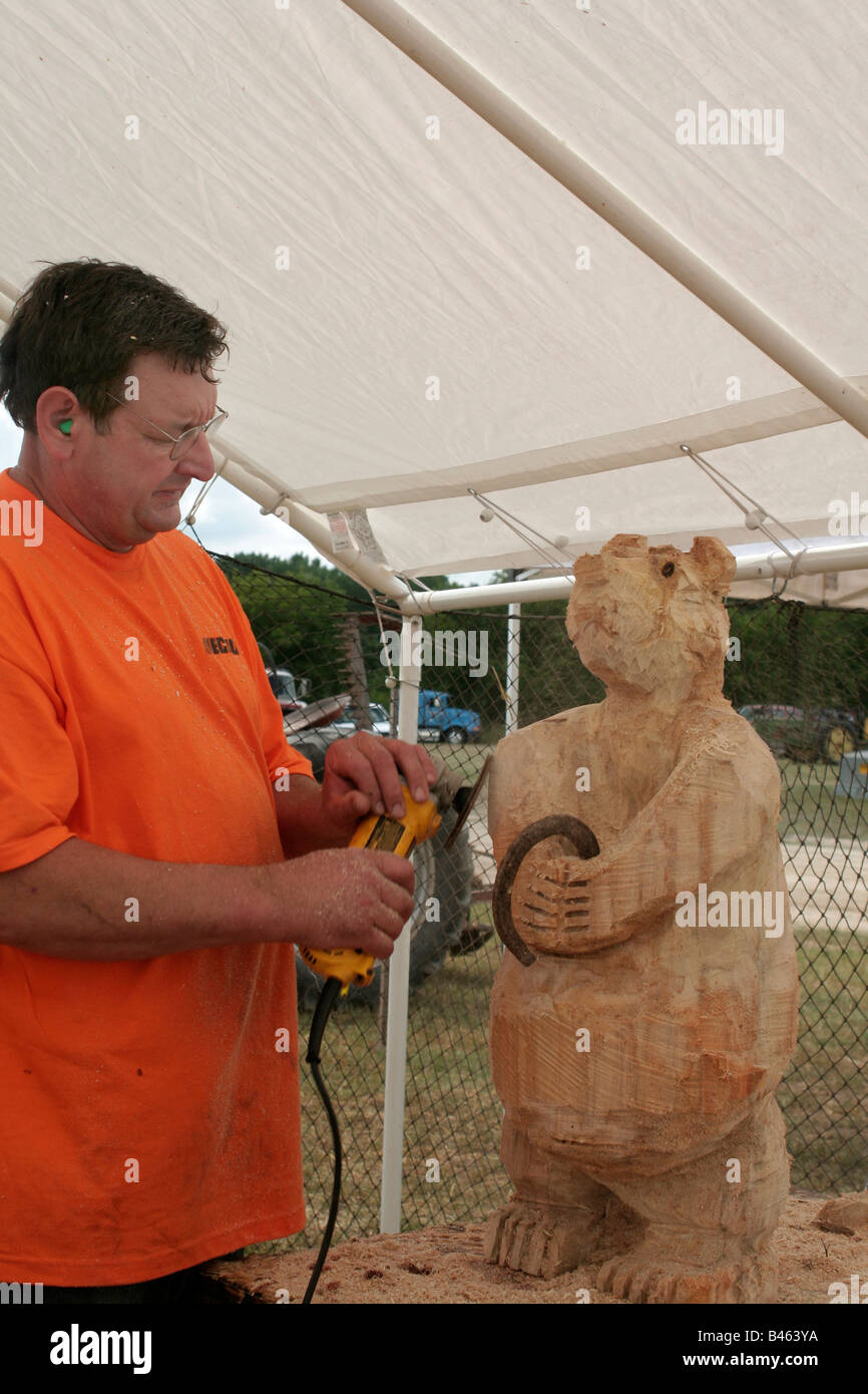 Chain saw carver finishes creation with disk sander Stock Photo
