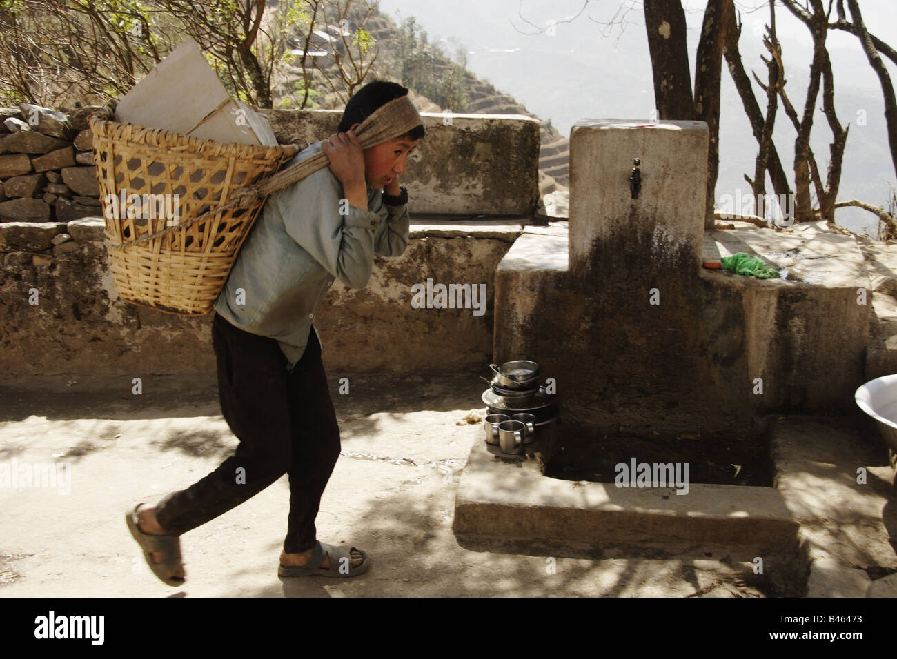Young boy carrying supplies in the hills of Nepal Stock Photo