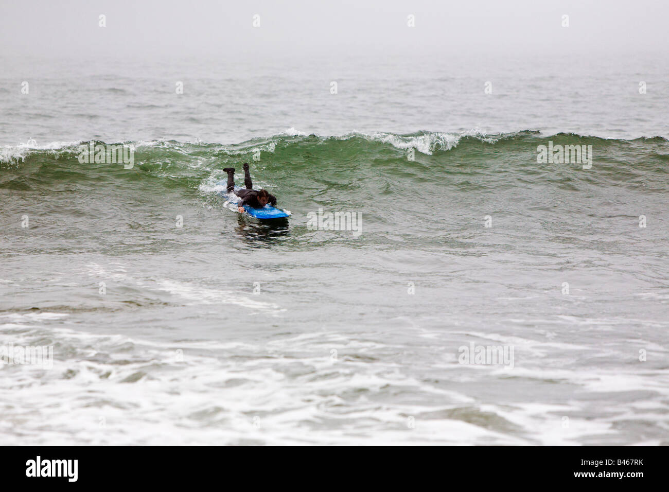 Surfing waves of Far Rockaway Beach during very foggy day New York USA Stock Photo