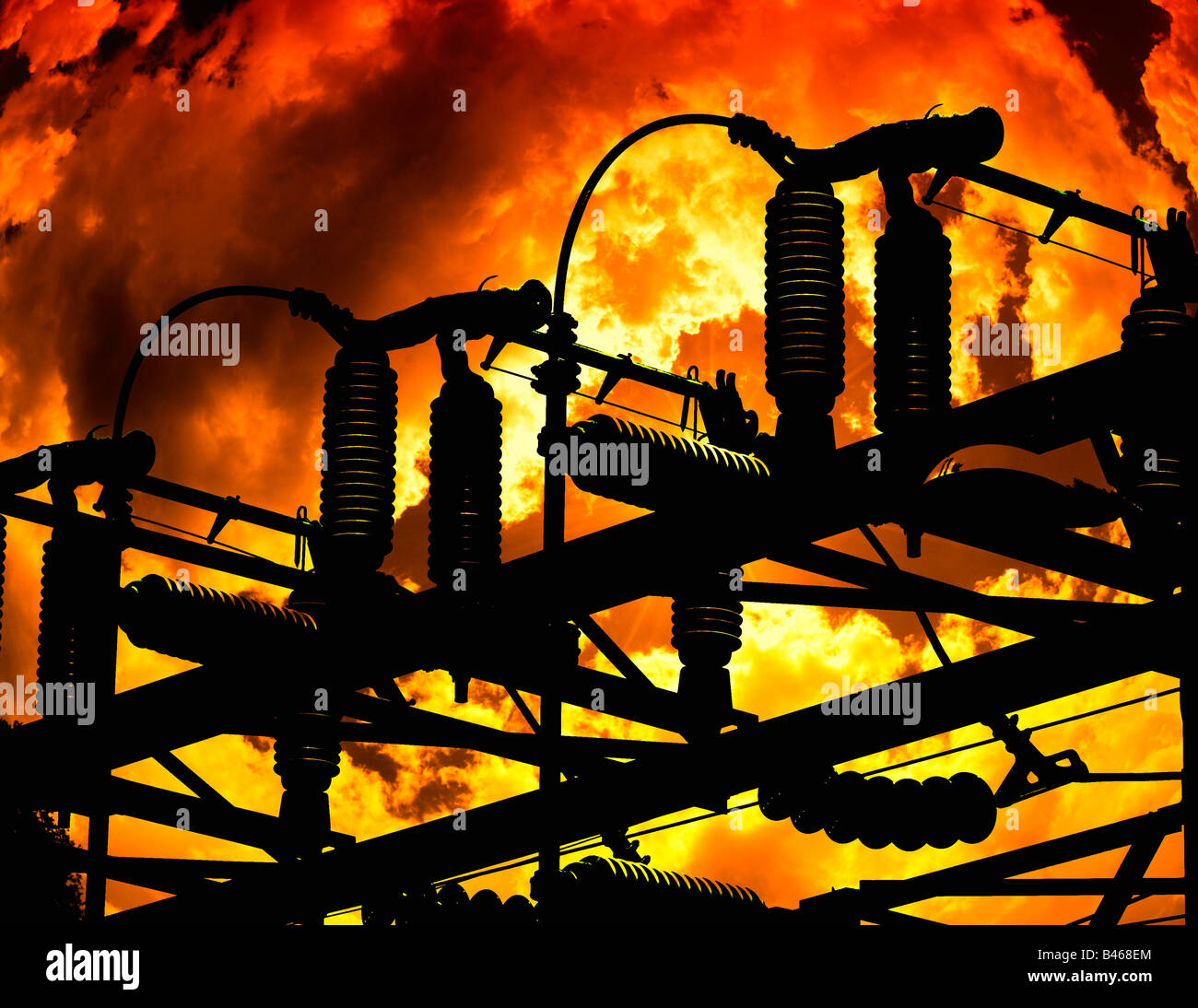 electric power substation silhouetted against large fire Stock Photo