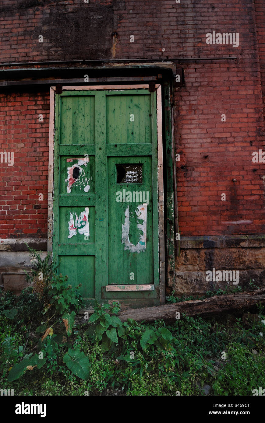 A Battered Green Door Makes A Sharp Contrast Against A Worn Red