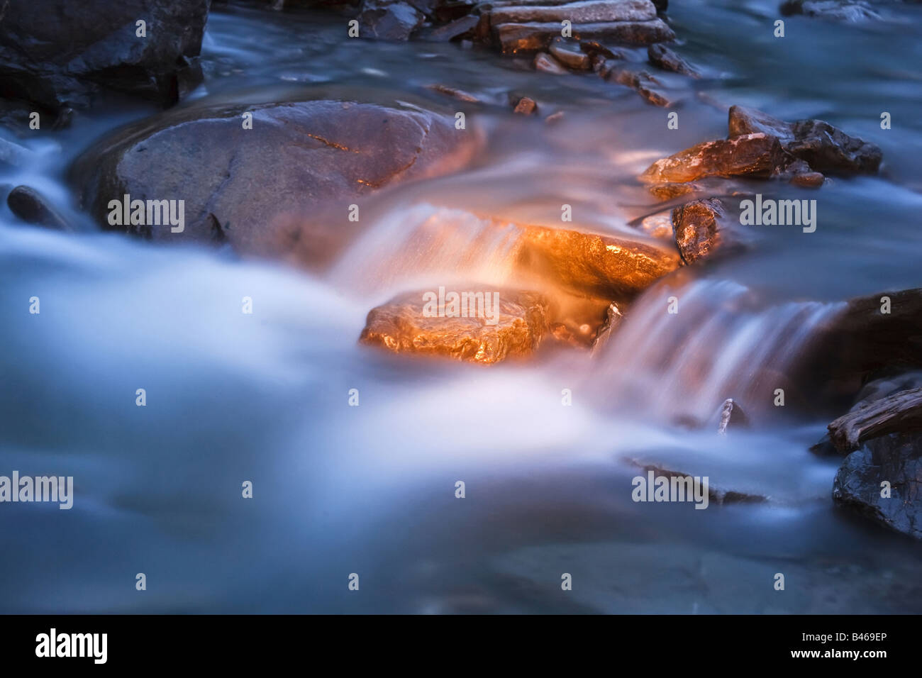blue river stream at night with golden light on rocks Stock Photo