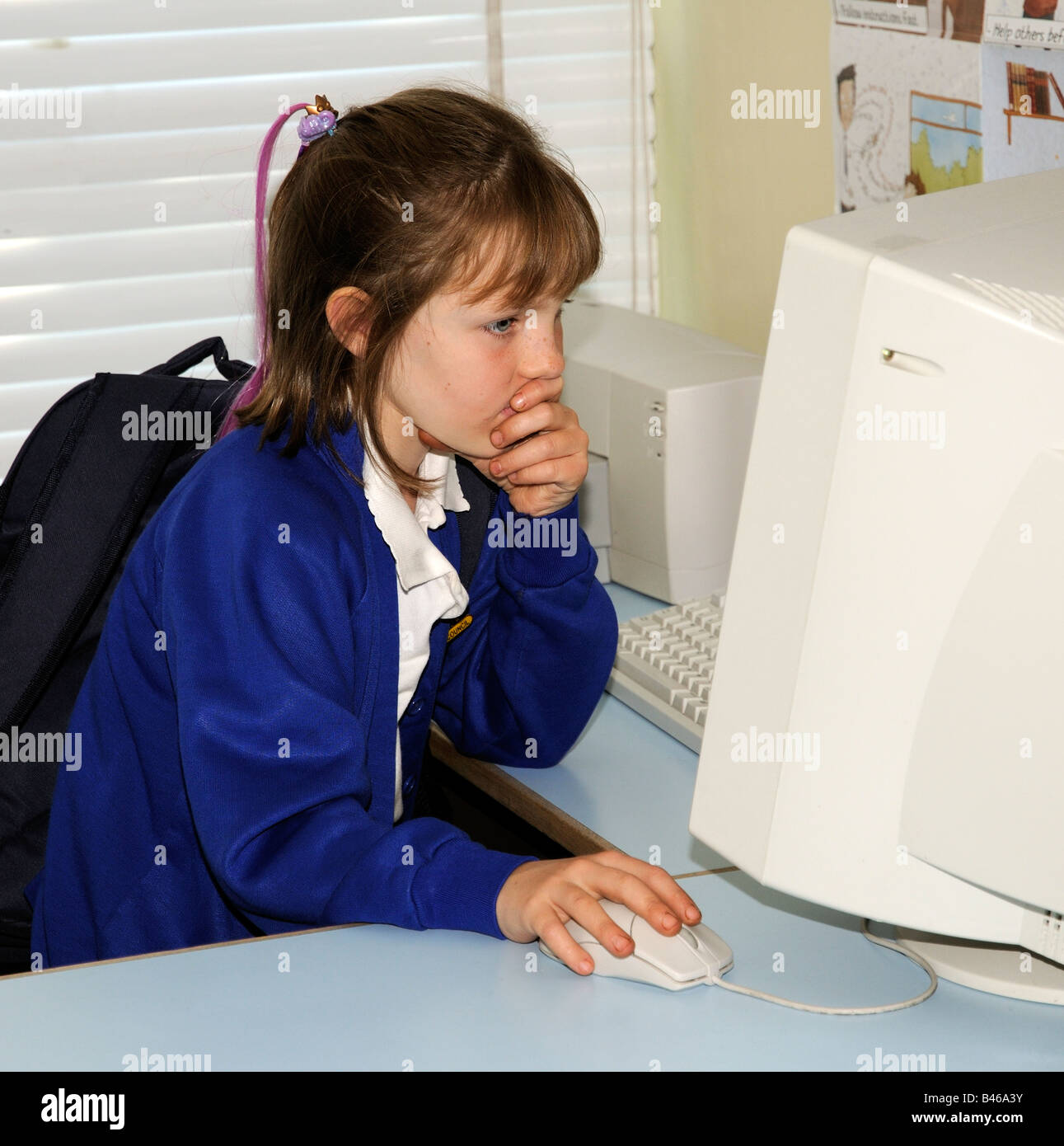 Child using a computer and looking at the monitor screen in a school