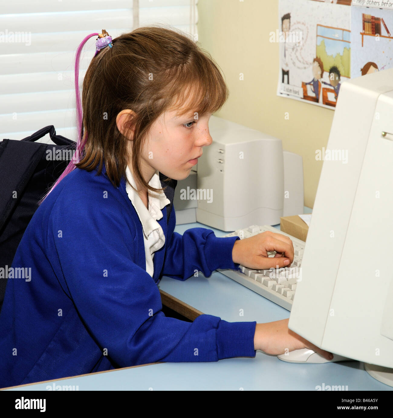 Child using a computer and looking at the monitor screen in a school