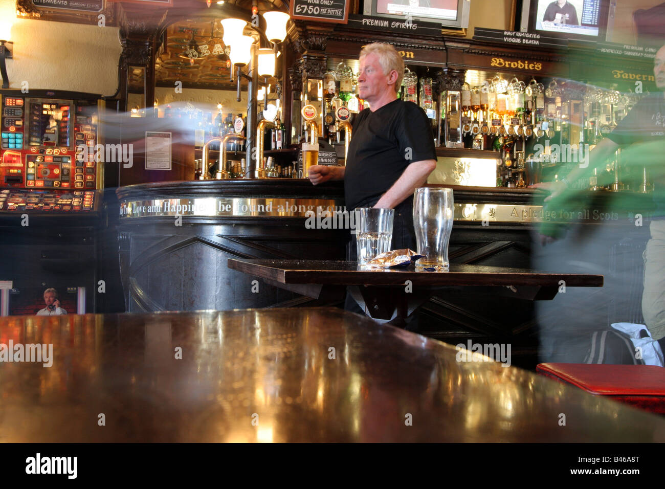 Single man standing at the bar whilst people move past like ghosts