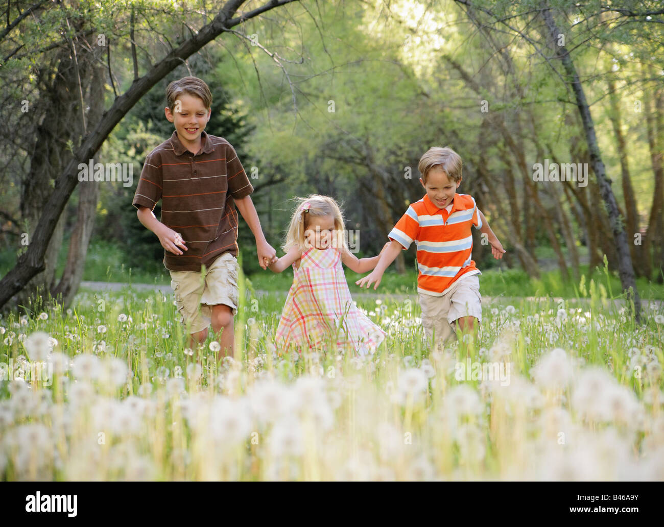 three children holding hands and running together in nature Stock Photo ...