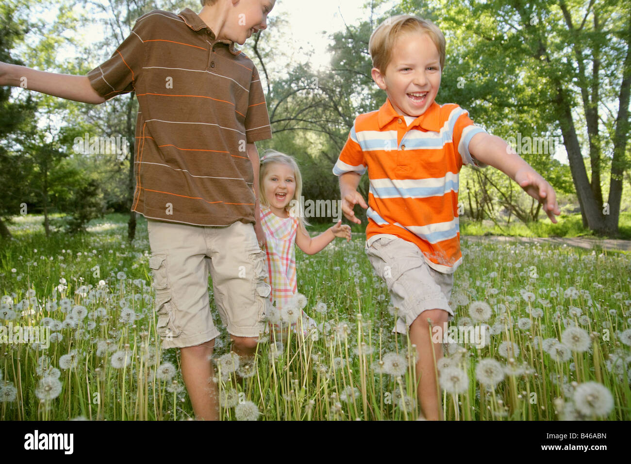 three children holding hands and running together in nature Stock Photo ...