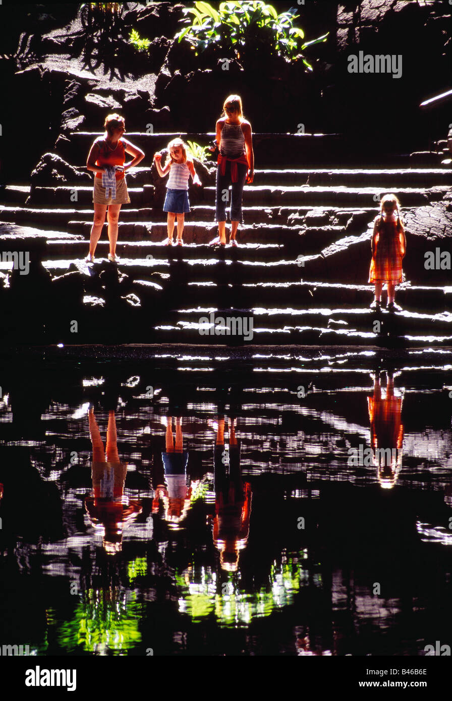 Four people and their reflections on water. Jameos del Agua cave. Lanzarote island. Canary Islands. Spain. Stock Photo