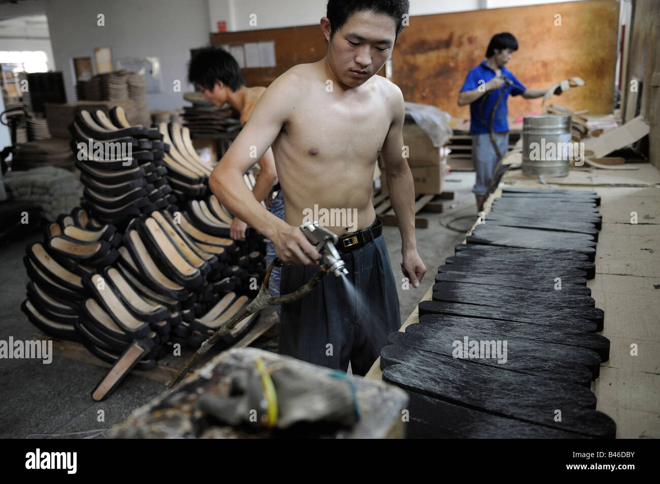 Laborers spray glue for office chairs at a Taiwan capital furniture