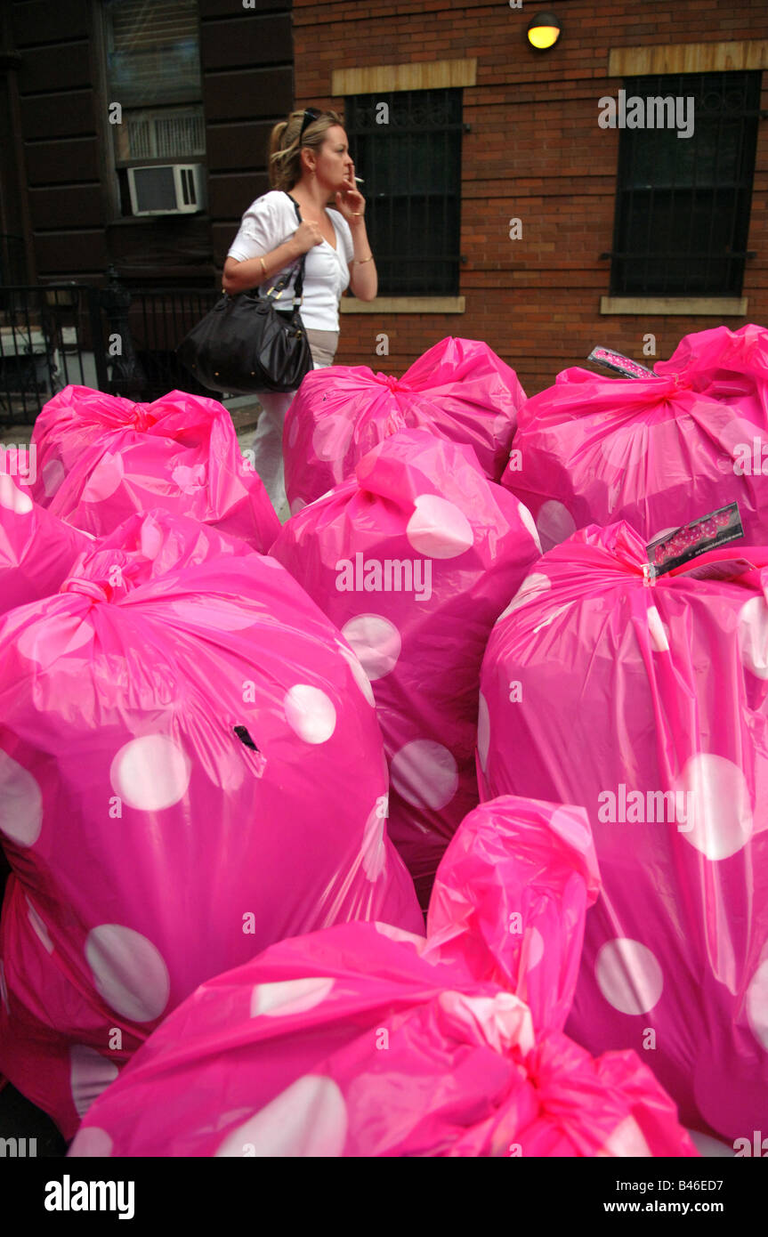 Colorful pink polka dot plastic trash bags are piled on the street
