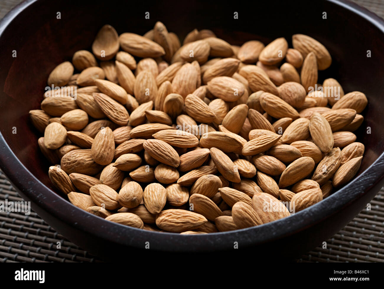 Organic raw almonds in a wooden bowl Stock Photo