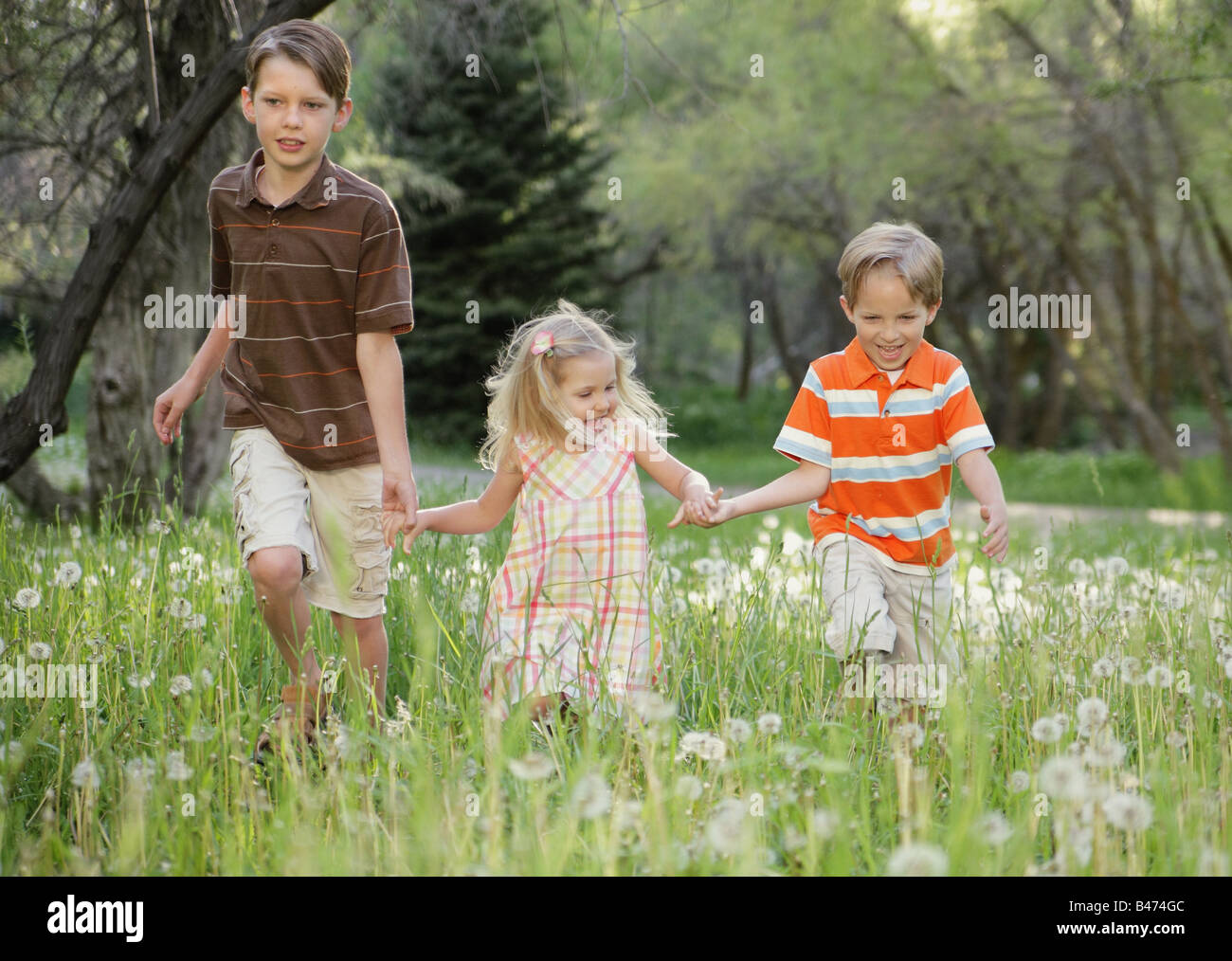 three children holding hands and running together in nature Stock Photo ...