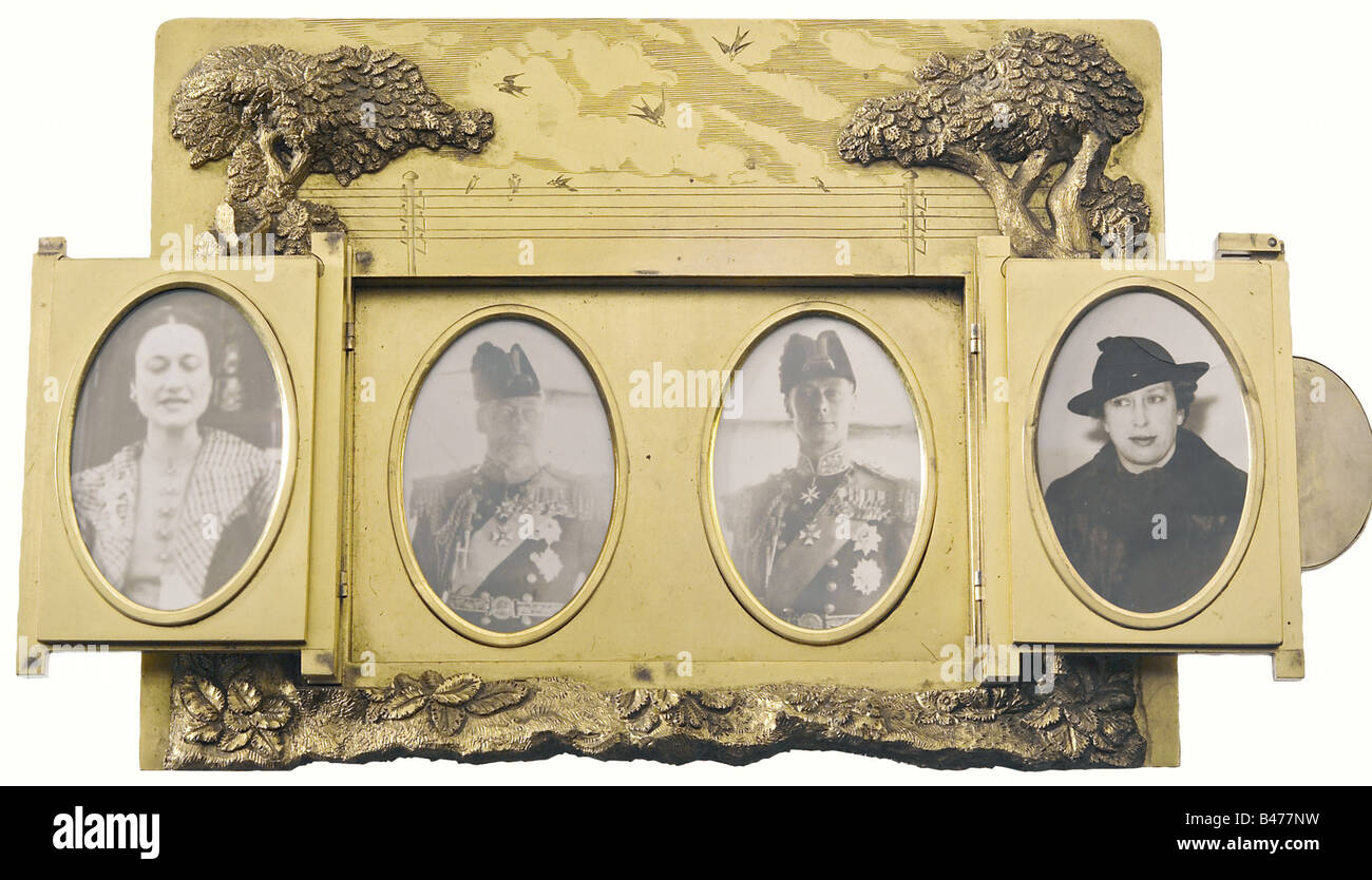 Edward, Duke of Windsor, framed photographs of the Windsors and Wallis Simpson. In the middle are King George V (1865 - 1936) and Edward, Prince of Wales (1894 - 1972) in Admiral's uniform of the Royal Navy, on the left side Wallis Warfield Simpson (1896 - 1986), on the right Princess Royal Mary, Duchess of Harewood (1897 - 1965), Edward's sister. Gilt bronze. Very appealingly worked in the shape of a manorial gate, framed by a pair of leafed trees with the inlaid, blue enameled inscription 'Please shut these gates'. In the centre the Duke's crowned monogram 'E, Stock Photo
