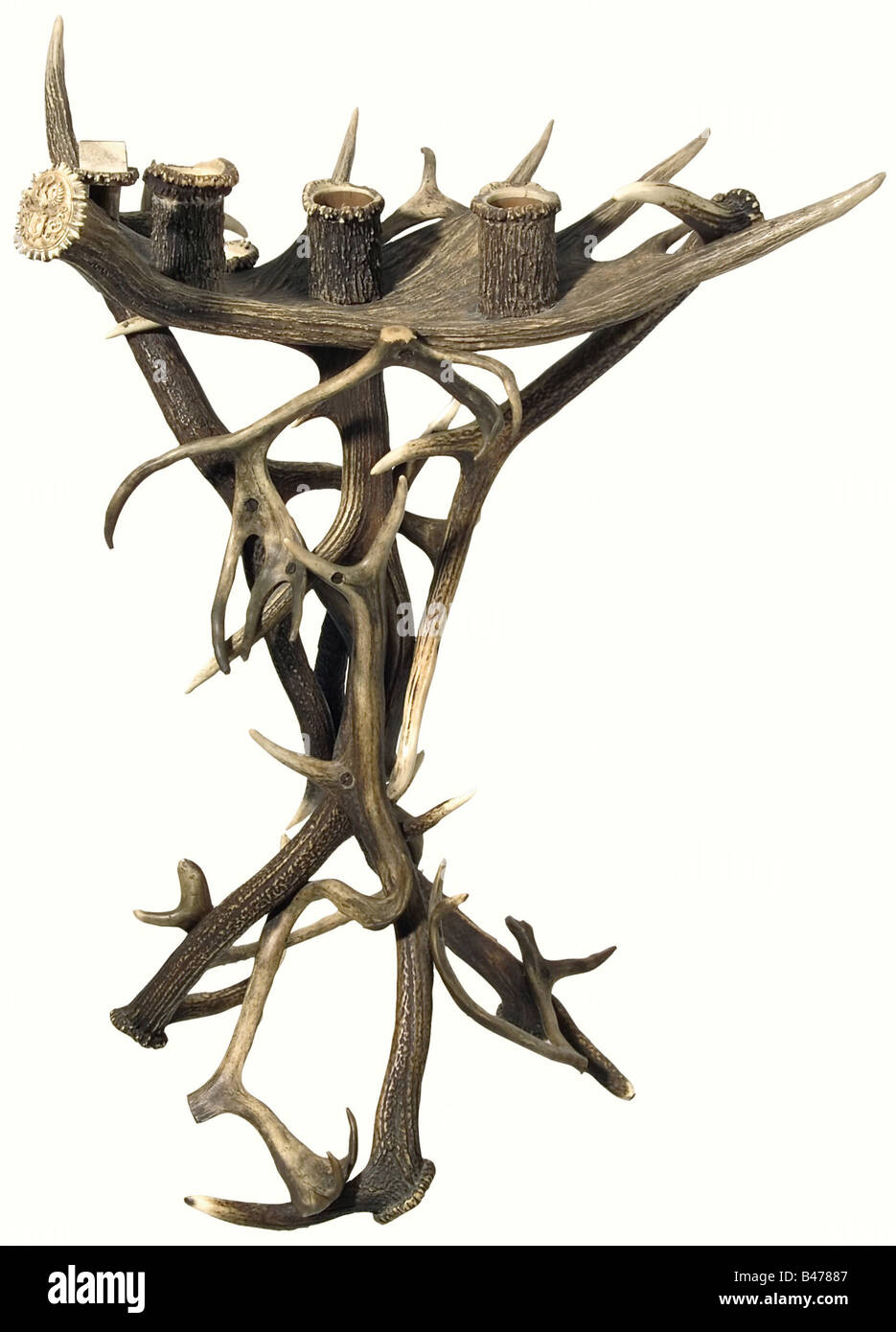 Hermann Göring - a hunter's smoking table., Three wood-lined, horn containers for cigars, cigarillos, cigarettes, and matches mounted on a massive palmate section of fallow deer antler crowning magnificent red stag antlers screwed together. One piece of antler serves as an ashtray, and the rosette bears the Göring family coat of arms. Height 94 cm. Width 64 cm. Cf. the hunter's barometer set into the palmate section of a fallow deer antler. Hermann Historica Auction 48, 22/23 April 2005, lot 7421, and the silver trophy goblet with fallow deer trophy, Schorfheid, Stock Photo