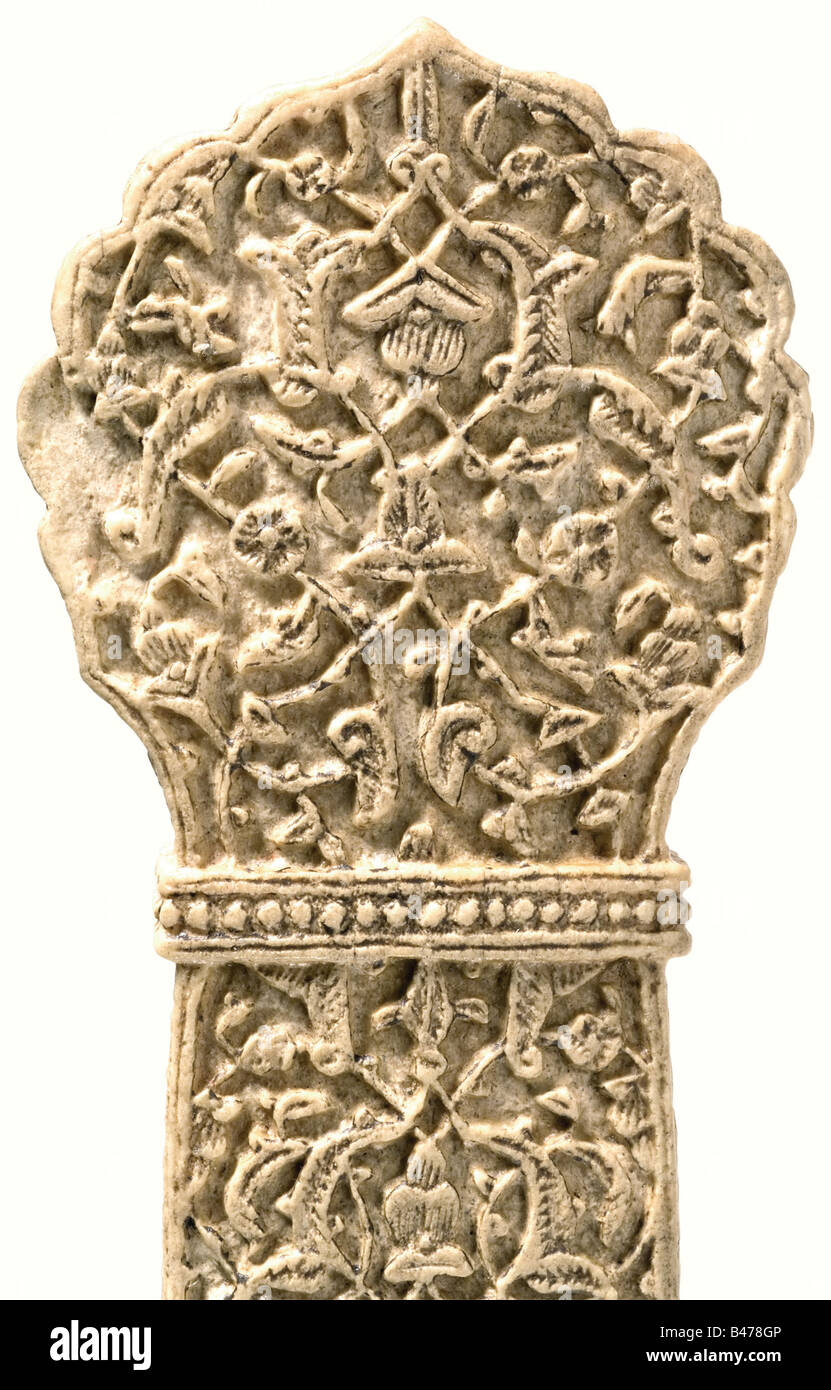A carved dagger grip, Ottoman, 16th Century or later(?). Slightly convex grip of walrus ivory with a palmetto shaped pommel. The surface is completely covered with deeply carved Artemisia stelleriana vines and flowers between two beaded columns. The rectangular socket has an oval hole and three small shrinkage cracks. Length 12.6 cm. Rare example from a small group of carved walrus ivory grips. There are similar pieces in the British and Victoria-and-Albert Museums in London, a private Saudi-Arabian collection, in the Dresden Historical Museum (complete dagger), Stock Photo