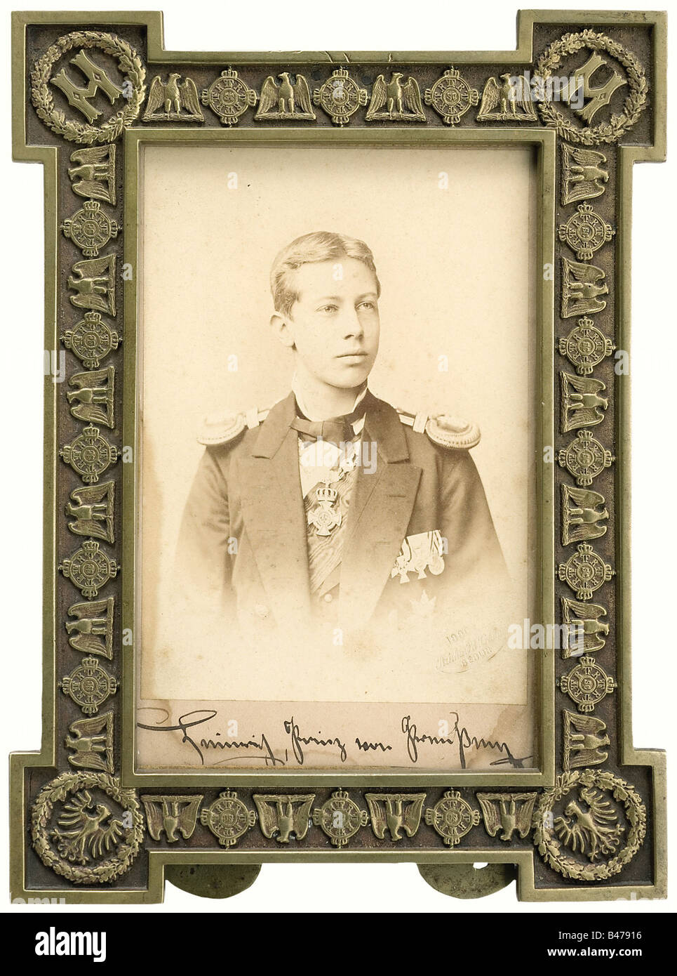 Prince Heinrich - a presentation frame, with a photo of the Prince in naval uniform. The photograph is dated at the lower right '1880' and inscribed by hand beneath 'Heinrich, Prinz von Preußen' (Heinrich, Prince of Prussia). Bronze frame with the intial 'H' in the upper corners, an eagle in the lower ones, and surrounded by the neck chain for the Order of the Black Eagle. The upper edge has traces of a mounting for a crown(?). Inscribed 'C.H. Preetz' on the back. 16.5 x 22 cm. people, 19th century, Prussian, Prussia, German, Germany, militaria, military, objec, Stock Photo