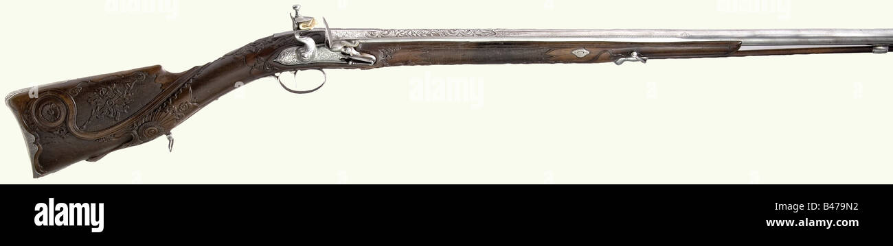 A splendid flintlock musket, Balkan/Turkish, circa 1820. Two-stage barrel, octagonal breech section then round with a sighting flat and a smooth bore in 15.5 mm calibre. Lavishly chiselled and engraved trophy decoration on the breech. Front sight missing. Re-converted lock with cut and engraved decoration. The cock has been repaired at one place. Lavishly carved walnut half stock with martial trophies and crescent moons amid vine decoration. Cut and engraved iron furniture. Wooden ramrod with horn tip. Length 123 cm. historic, historical, 19th century, Ottoman , Stock Photo