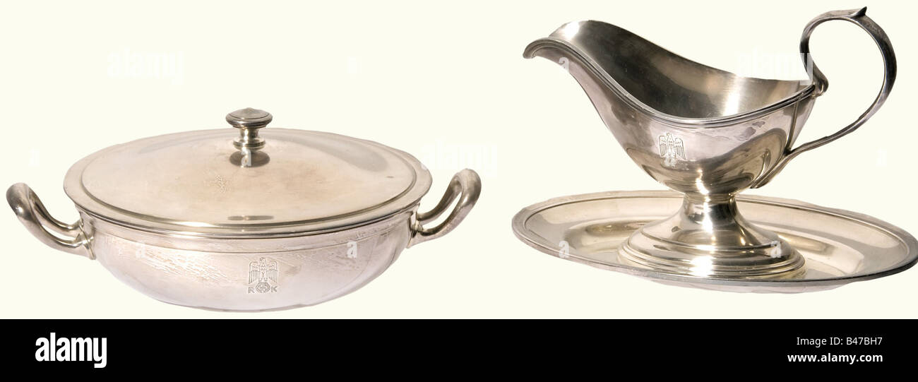 Adolf Hitler, a vegetable bowl and a sauce boat from the table silver of the Neue Reichskanzlei, Berlin Both pieces of tableware are hard silver-plated and both have the engraved party eagle above 'RK' on the obverse side and the maker's mark 'Wellner' on the bottom. The vegetable bowl has additional markings, '140 cl.' and '42' in a circle. Height 12 cm, diameter 30 cm. The sauceboat has '40 cl.' and '30' in a circle. Height 17.5 cm, width 26.5 cm. historic, historical, 1930s, 1930s, 20th century, NS, National Socialism, Nazism, Third Reich, German Reich, Germ, Stock Photo