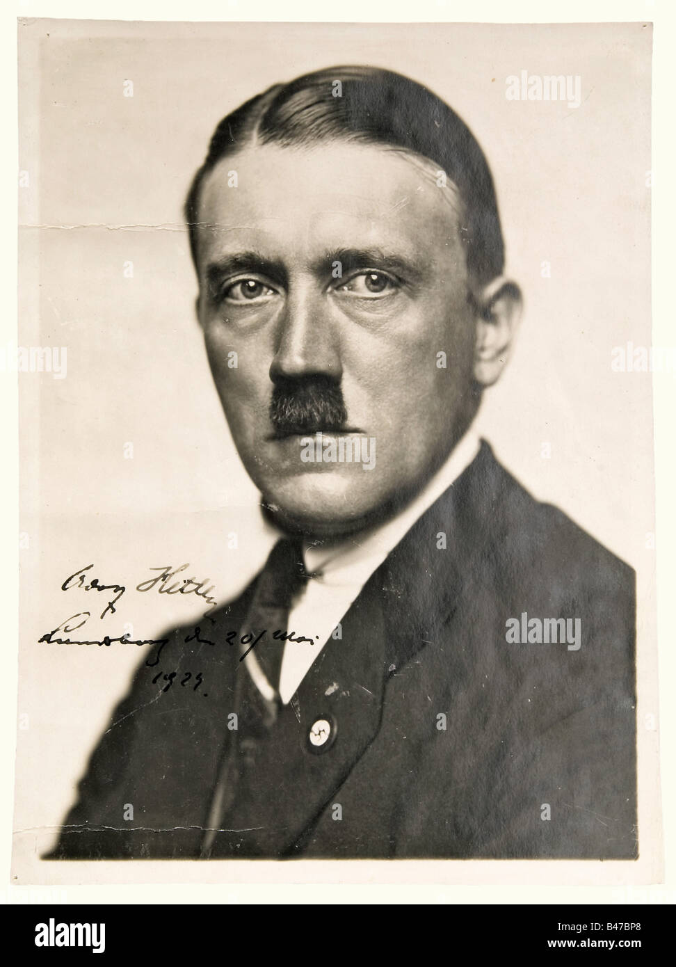 Adolf Hitler, a portrait photograph with an autograph signature Landsberg, 20 May 1924. Large format Hoffmann photo. Half portrait, signed 'Adolf Hitler - Landsberg on 20 May 1924' at the lower left in dark ink. Stamped on the back, 'Photo-Bericht Hoffmann, Schellingstr. 50'. Two craqueleures in the photo, traces of paste on the back. 23.5 x 17.5 cm. There is also a handwritten letter by Roger Showalter to the famous American dealer Ben Swearingen, dated 11 July, but no year, ca. middle of the 70s, offering this photo for 2,000 dollars. In the letter Showalter , Stock Photo