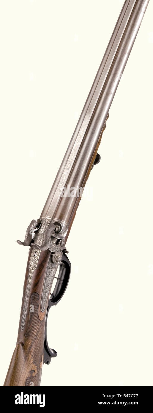 A double-barrelled percussion shotgun, Johann Adam Kuchenreuter, Regensburg, circa 1830. Side-by-side Damascus barrels with smooth bore in 17 mm calibre with a silver bead. 'J. Adam Kuchenreuter in Regensburg' is inlaid in silver on the midrib. The locks have fine ornamental engraving and folding buffers. Carved and checkered walnut half stock with a nose cap shaped like a monster's head. The trigger guard is of blackened wood. Somewhat shortened wooden ramrod with a horn tip. Length 116 cm. Johann Adam Kuchenreuter, Regensburg , 1794 - 1869 was court gunsmith , Stock Photo
