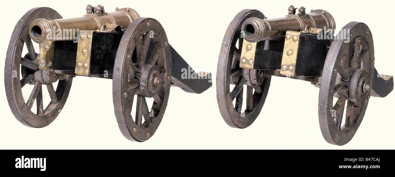 A pair of model cannons, German, circa 1700. Bronze barrels in several sections with hoop structure and reinforced muzzles. Side mounted trunnions. There are two sculpted hooks in the shape of dolphins on top of each. The breeches have fluted decoration and oval finials. Later hard wood gun carriages with strap mountings of sheet brass, and moveable iron-covered spoked wheels. Barrel length of each 41 cm. Total length of each 66 cm. historic, historical, 18th century, cannon, cannons, artillery, firearm, fire arm, firearms, fire arms, weapons, arms, weapon, arm, Stock Photo