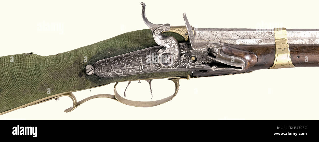 An air rifle, German, circa 1760. Octagonal barrel with seven groove rifling in 10 mm calibre with dovetailed brass sights and engraved rococo ornamentation on the breech. Flintlock chiselled with hunting scenes in relief with set trigger and automatic shot counter. Walnut full stock with horn nosecap and a cloth covered, iron, compressed air reservoir in the buttstock. Brass furniture decorated with rococo and hunting ornamentation in relief. Later ramrod with horn tip. Length 112.5 cm. Early, lavishly decorated air rifle with a rare shot counter. historic, hi, Stock Photo