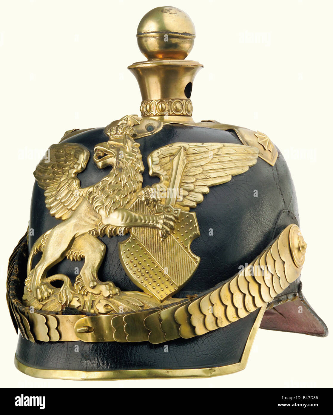 Baden: A helmet for officers, of artillery, as worn circa 1870. The crown of the leather skull is somewhat sunken, the left side is torn above the ear, and the lacquer finish is crazed. The large plate is of the older pattern. Flat chinscales are attached to a large officers' style cockade. The liner and the lining of the peak are of black leather, and show some signs of wear and ageing. Size 57. historic, historical, 19th century, object, objects, stills, clipping, clippings, cut out, cut-out, cut-outs, Stock Photo