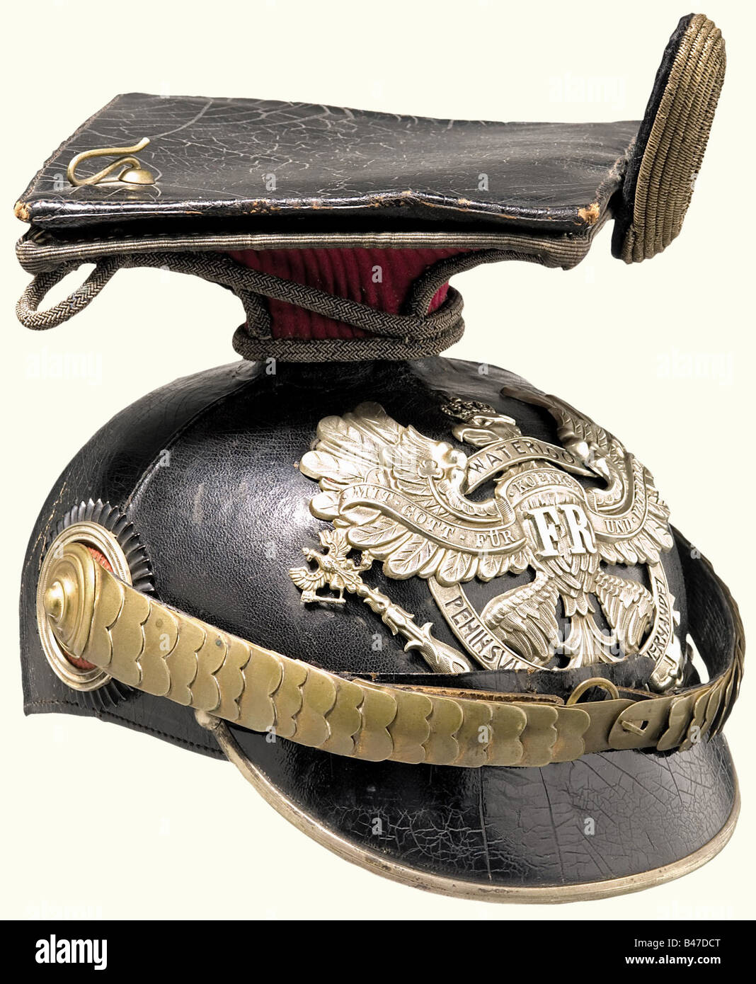 A czapka for officers, of the 2. Hanoverian Uhlan Regiment No. 14 A four piece, black lacquered leather skull (lightly warped) with silver brim edging and emblem with the scroll "Waterloo Peninsula Garzia Hernandez", cambered, golden metal chin scales with pin rosettes. Officer cockade. Brown sweatband with greenish, ribbed silk lining. Complete with the crimson parade cover and officer's field badge. historic, historical, 19th century, uniform, uniforms, piece of clothing, clothes, outfit, outfits, helmet, helmets, cap, caps, headpiece, headpieces, object, obj, Stock Photo