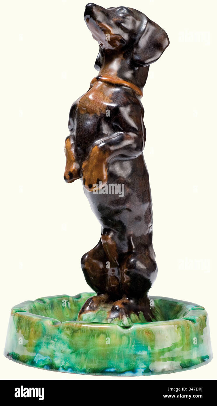 A Dachshund ashtray, from the Imperial Majolika Manufacture Cadinen. Plastically modelled figure with multi-couloured glaze. Design by Max Bezner. Manufacture mark on the base. Height 20 cm. Very rare. Max Bezner worked for Cadinen and created mostly busts of Emperor Wilhelm II. Apart from the dachshund (no. 393), he made only very few animal sculptures, cf. 'Cadinen', exhibition catalogue Schlossmuseum Marienburg, pp. 58, 105 and illustration with plinth instead of ashtray, p. 156. fine arts, people, 19th century, German Empire, Germany, Imperial, ob, Artist's Copyright has not to be cleared Stock Photo