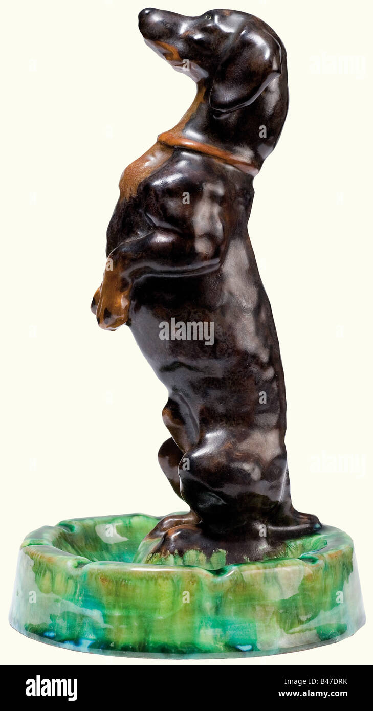 A Dachshund ashtray, from the Imperial Majolika Manufacture Cadinen. Plastically modelled figure with multi-couloured glaze. Design by Max Bezner. Manufacture mark on the base. Height 20 cm. Very rare. Max Bezner worked for Cadinen and created mostly busts of Emperor Wilhelm II. Apart from the dachshund (no. 393), he made only very few animal sculptures, cf. 'Cadinen', exhibition catalogue Schlossmuseum Marienburg, pp. 58, 105 and illustration with plinth instead of ashtray, p. 156. fine arts, 19th century, German Empire, Germany, Imperial, object, ob, Artist's Copyright has not to be cleared Stock Photo