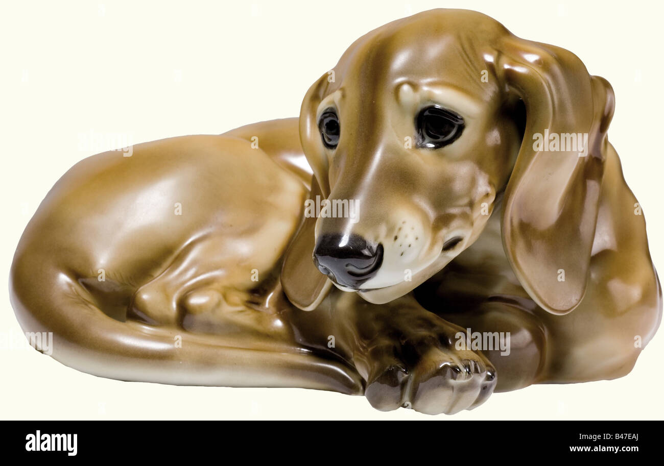 A dachshund., A coloured glazed figure of a recumbent dachshund. The bottom bears the model number '13', the manufacturer's mark in underglaze green in an octagon, and the signature, 'T. Kärner'. Height 11 cm.' fine arts, 1930s, 1930s, 20th century, porcelain, chinaware, object, objects, stills, clipping, clippings, cut out, cut-out, cut-outs, Additional-Rights-Clearance-Info-Not-Available Stock Photo