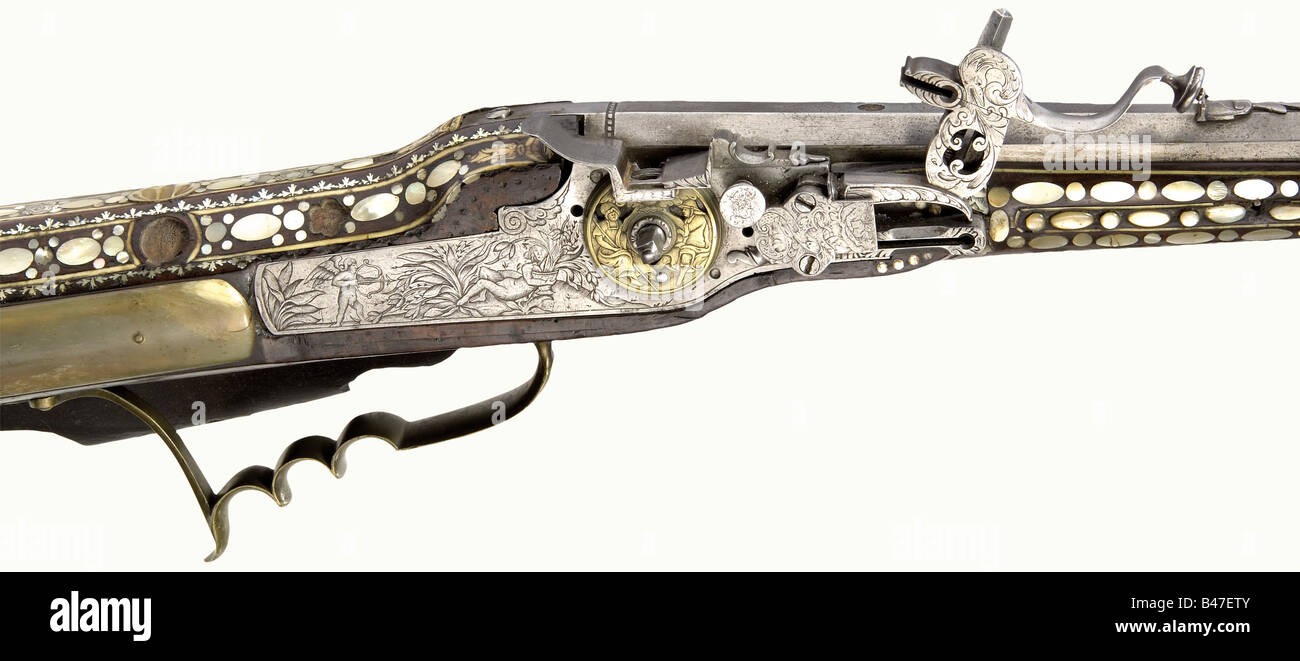 A wheellock rifle, Johann Entzinger, Vienna, inscribed '1687'. Octagonal, slightly swamped barrel with seven groove rifling in 13 mm calibre. Dovetailed sights. Signed 'JOHANN ENTZINGER' (worn) in front of the breech with brass filled marks (Stöckel No. 7358) Iron wheellock with beautiful floral and figure engraving and an open work brass wheel cover. Walnut full stock with profuse inlays of mother-of-pearl and bone. The cheek piece displays the sun, moon, and stars. The forearm is entirely covered with fine decorative oval and round pieces, some raised. The da, Stock Photo