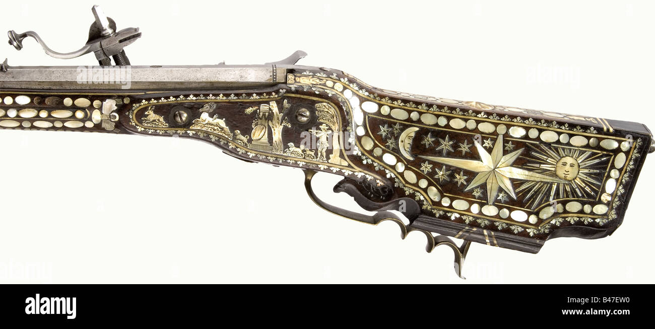 A wheellock rifle, Johann Entzinger, Vienna, inscribed '1687'. Octagonal, slightly swamped barrel with seven groove rifling in 13 mm calibre. Dovetailed sights. Signed 'JOHANN ENTZINGER' (worn) in front of the breech with brass filled marks (Stöckel No. 7358) Iron wheellock with beautiful floral and figure engraving and an open work brass wheel cover. Walnut full stock with profuse inlays of mother-of-pearl and bone. The cheek piece displays the sun, moon, and stars. The forearm is entirely covered with fine decorative oval and round pieces, some raised. The da, Stock Photo