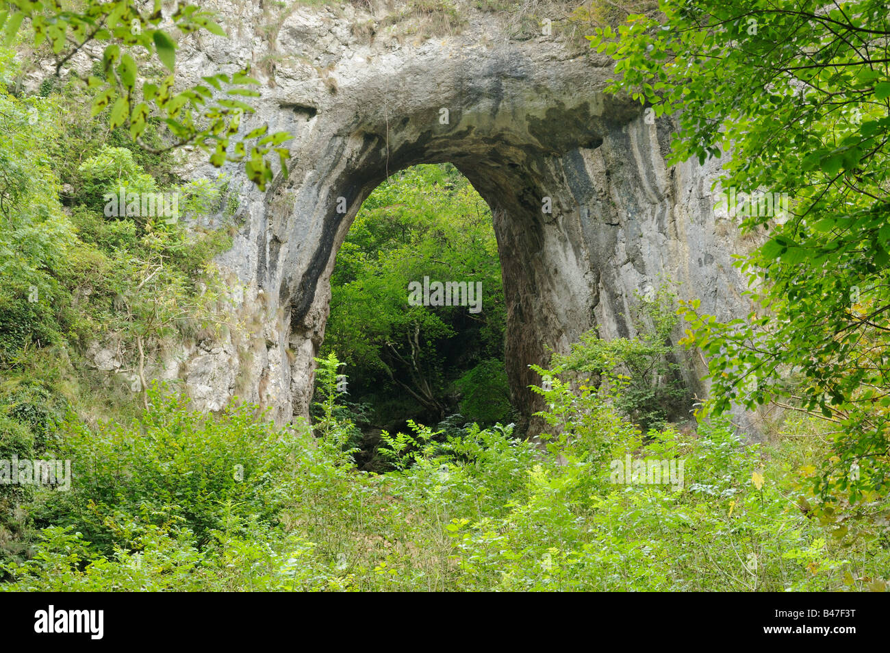 Natural rock arch leading to Reynards Cave Dovedale Peak District UK Stock Photo