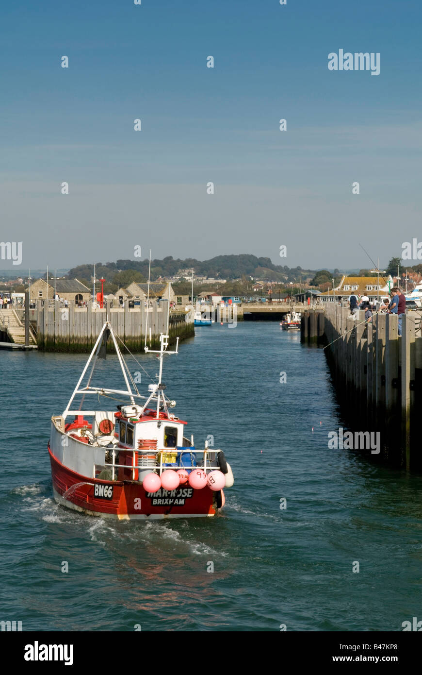 Fishing boat returning to the harbour at West Bay, Dorset, England, UK ...