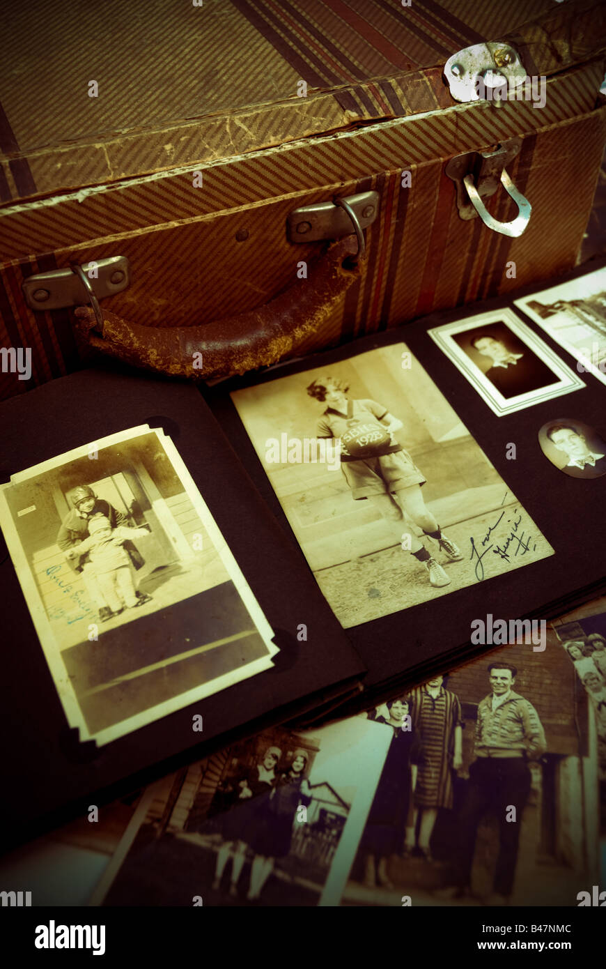 A battered old antique suitcase with vintage photographs from an old photo album. Stock Photo
